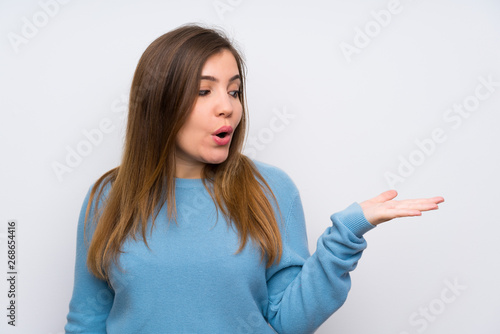 Young girl with blue sweater holding copyspace imaginary on the palm