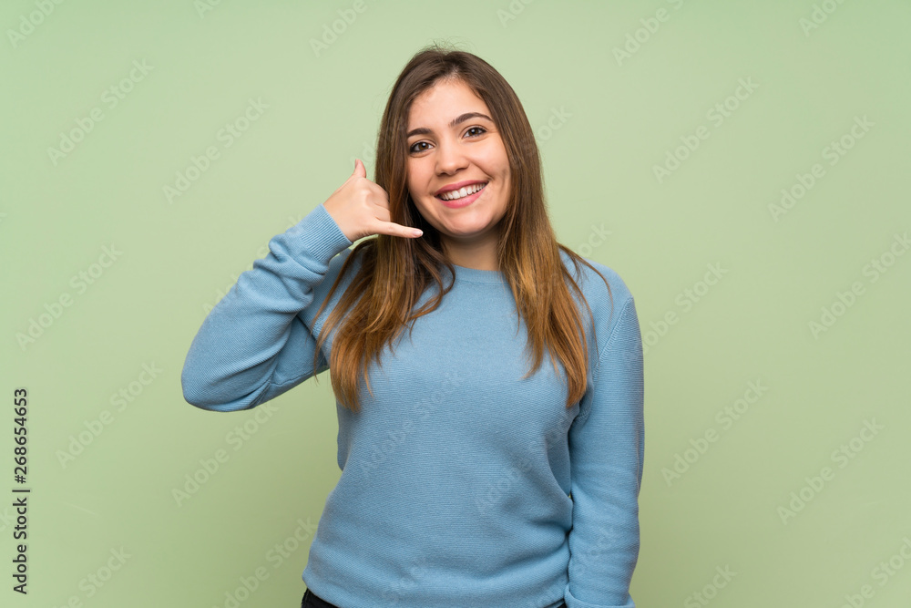 Young girl over green wall making phone gesture. Call me back sign Young girl over green wall making phone gesture. Call me back sign