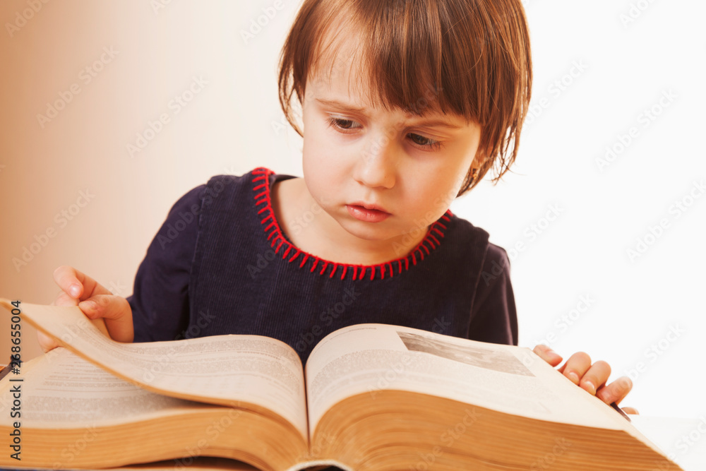 Little cute child girl watching a book as symbol of science, education and knowledge Little cute child girl watching a book as symbol of science, education and knowledge