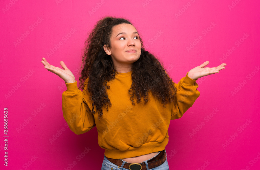 Teenager girl over pink wall making doubts gesture Teenager girl over pink wall making doubts gesture