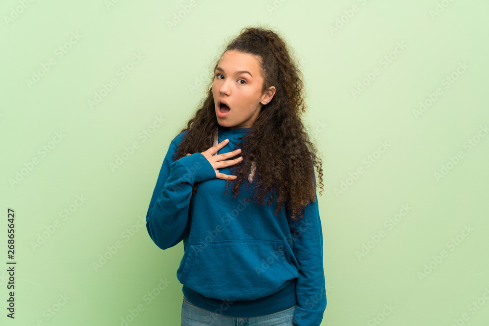 Teenager girl over green wall surprised and shocked while looking right Teenager girl over green wall surprised and shocked while looking right