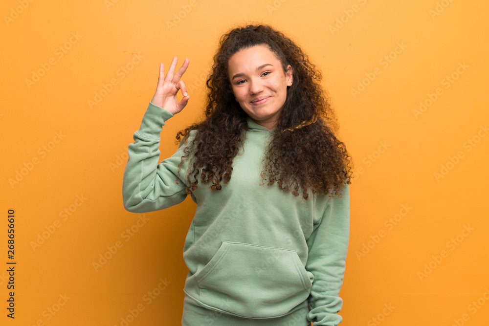 Teenager girl over ocher wall showing ok sign with fingers Teenager girl over ocher wall showing ok sign with fingers