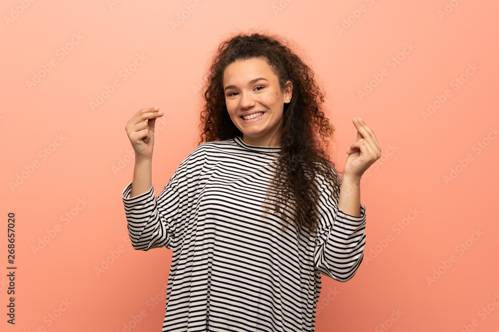 Teenager girl over pink wall making money gesture Teenager girl over pink wall making money gesture