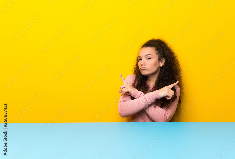 Teenager girl pointing to the laterals having doubts Teenager girl pointing to the laterals having doubts