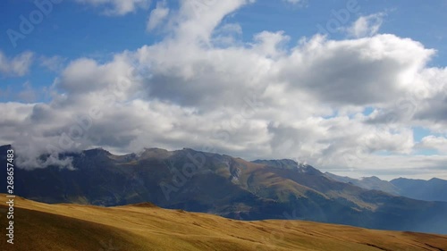 The movement of white cumulus clouds over the mountains on a sunny day on a background of bright blue sky. Abishir-Akhub Ridge and Gabula Plateau, Arkhyz, Caucasus, Russia. Time lapse photo