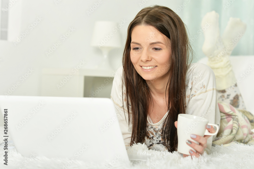 Young woman lying on bed with cup of coffee Young woman lying on bed with cup of coffee
