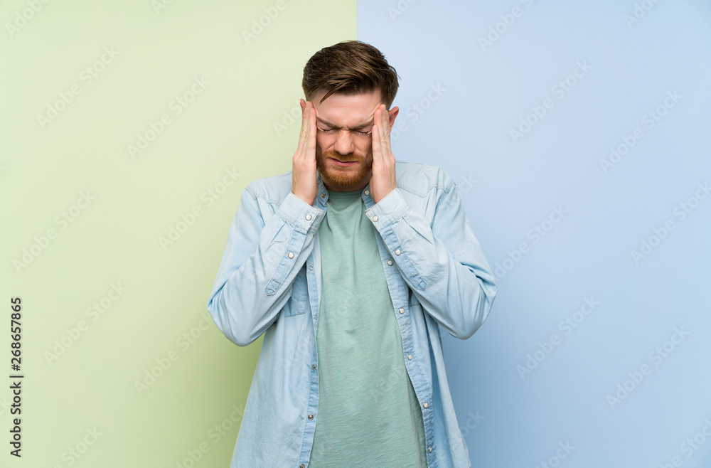 Redhead man over colorful background with headache Redhead man over colorful background with headache