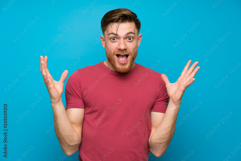 Redhead man on isolated blue wall with surprise facial expression Redhead man on isolated blue wall with surprise facial expression
