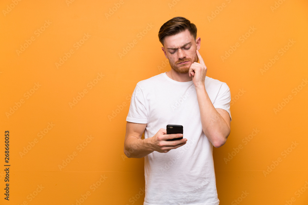 Redhead man over brown wall thinking and sending a message Redhead man over brown wall thinking and sending a message