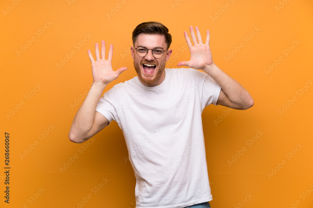Fototapeta premium Redhead man over brown wall with glasses and smiling