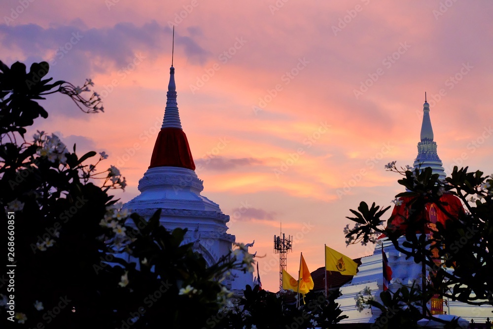 Silhouette colorful sky with clouds and two white pagodas with plumeria trees at Wat Pooramai, KohKret, Nonthaburi,Thailand