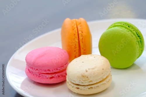 In senlective focus a group of macaroons,famous French dessert in a white plate with wooden dinning table  photo