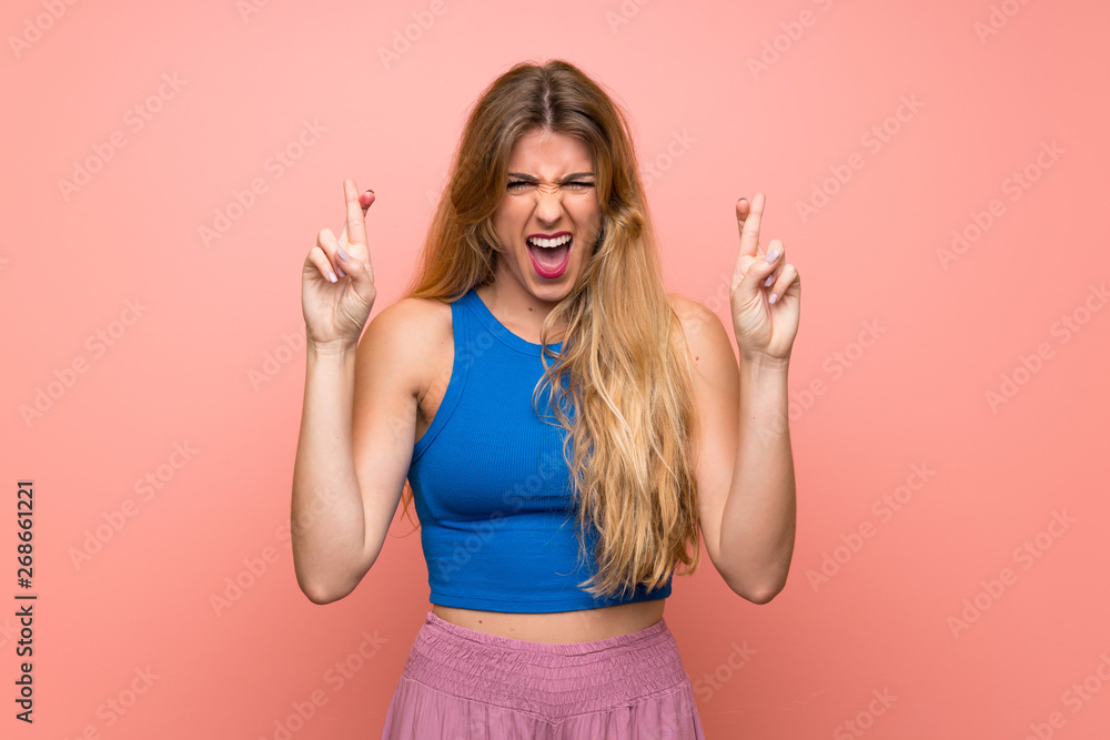 Young blonde woman over isolated pink background with fingers crossing Young blonde woman over isolated pink background with fingers crossing