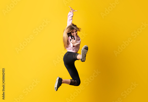 Urban Ballerina dancing over isolated yellow background and jumping