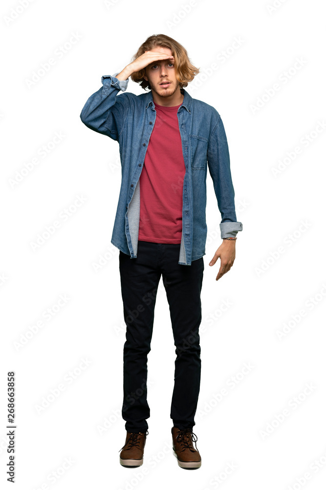 Full-length shot of Blonde man looking far away with hand to look something over isolated white background Full-length shot of Blonde man looking far away with hand to look something over isolated white background