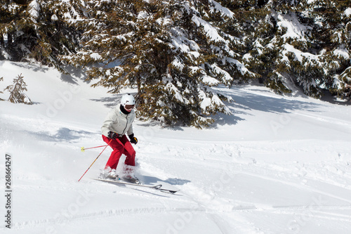 Skier skiing downhill during sunny day in high mountains