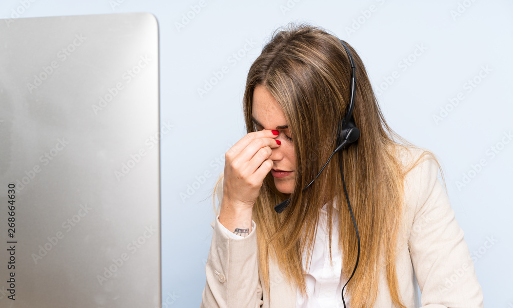 Young blonde telemarketer woman over isolated blue wall and stressed Young blonde telemarketer woman over isolated blue wall and stressed