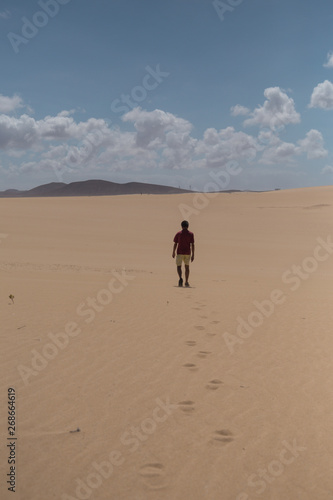 Man walks through sand dunes