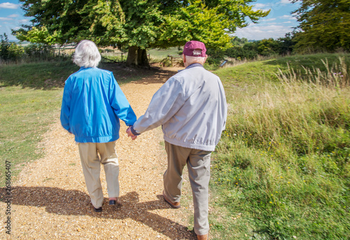 Elderly couple holding hands while visiting the British countryside.