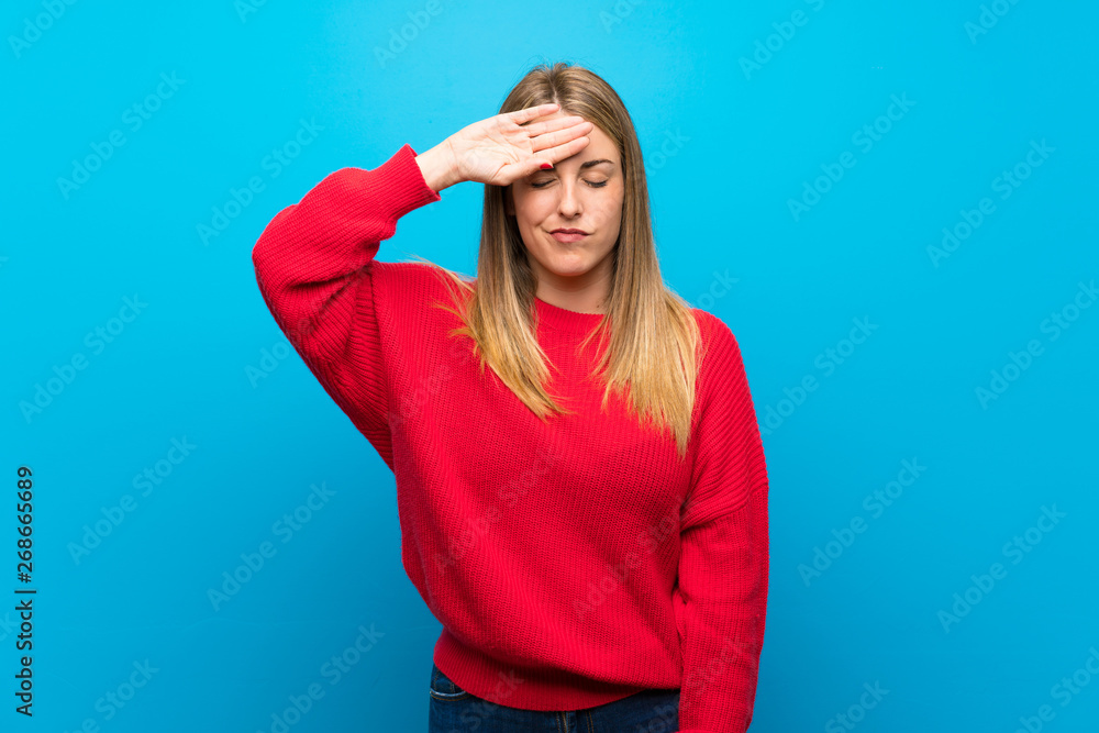 Woman with red sweater over blue wall with tired and sick expression Woman with red sweater over blue wall with tired and sick expression
