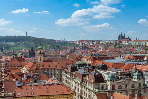 Outdoor sunny panoramic aerial scenery of rooftop in old town, city skyline, Charles Bridge tower and background range of mountain with Prague Castle and St. Vitus Cathedral in Prague, Czech Republic.