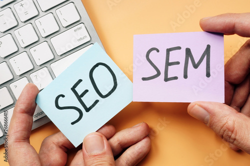 Hands holding cards with SEO and SEM.