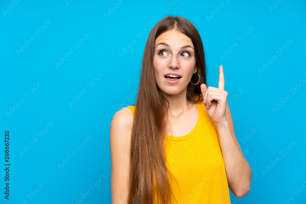 Young woman with long hair over isolated blue wall thinking an idea pointing the finger up Young woman with long hair over isolated blue wall thinking an idea pointing the finger up