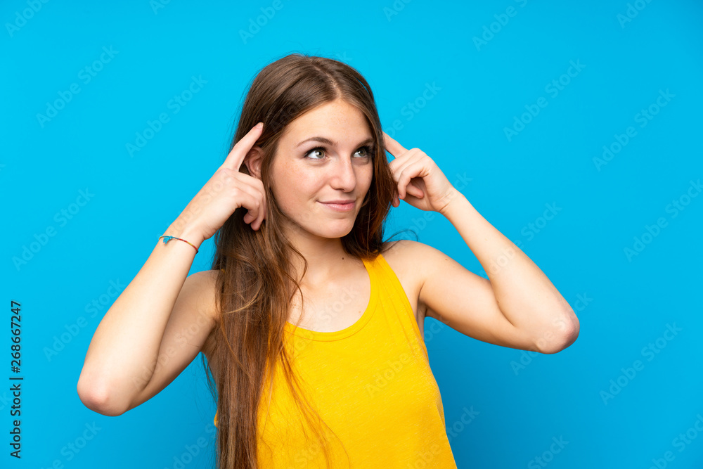 Young woman with long hair over isolated blue wall having doubts and thinking Young woman with long hair over isolated blue wall having doubts and thinking