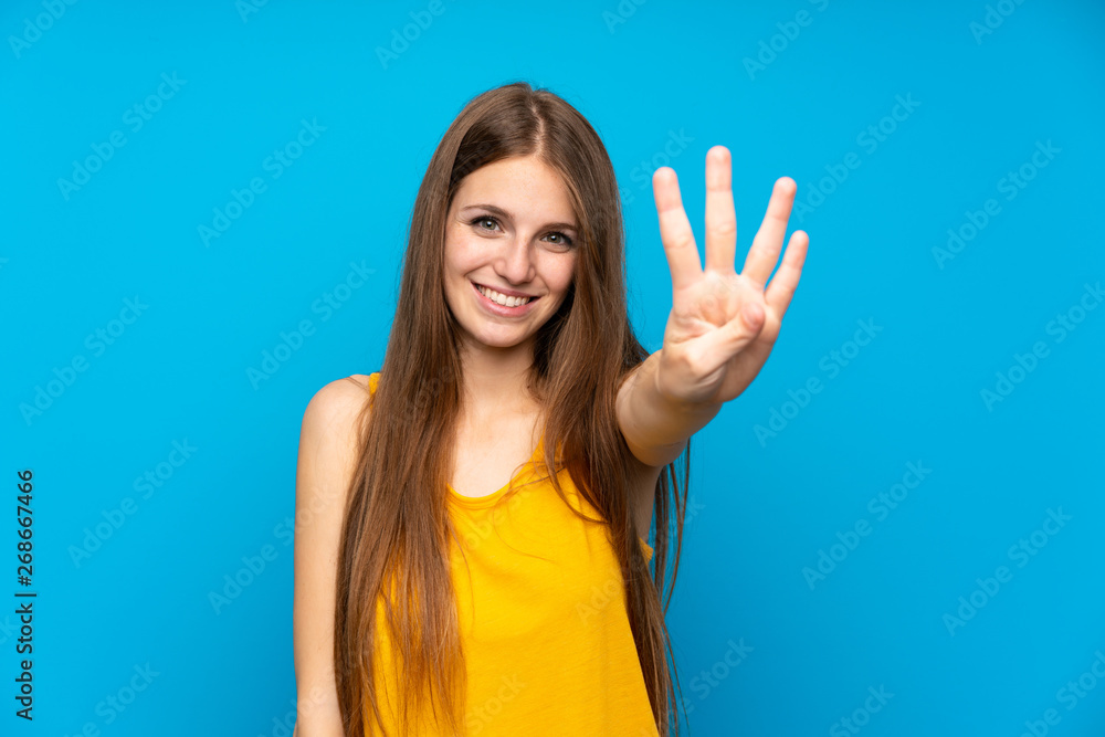 Fototapeta premium Young woman with long hair over isolated blue wall happy and counting four with fingers