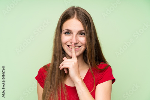 Young woman with long hair over isolated green wall doing silence gesture