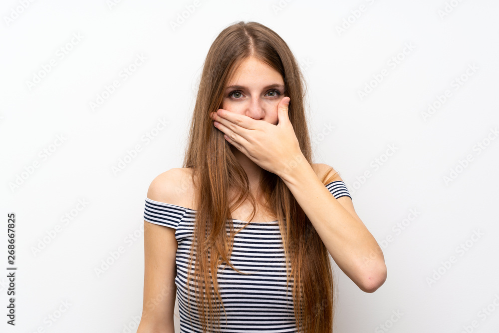 Young woman with long hair over isolated white wall covering mouth with hands Young woman with long hair over isolated white wall covering mouth with hands