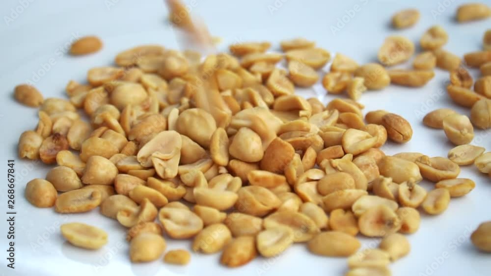 Slow motion of Roasted peanuts on grey background for advertising. Clean food good taste ideas concept. Selective focus and free space for text. Slow motion of Roasted peanuts on grey background for advertising. Clean food good taste ideas concept. Selective focus and free space for text.