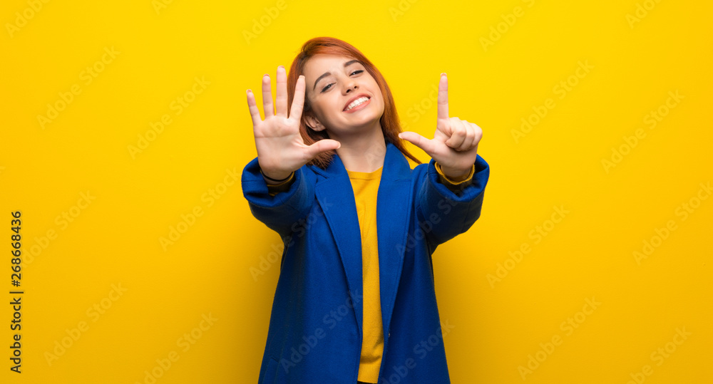 Young redhead woman with trench coat counting seven with fingers