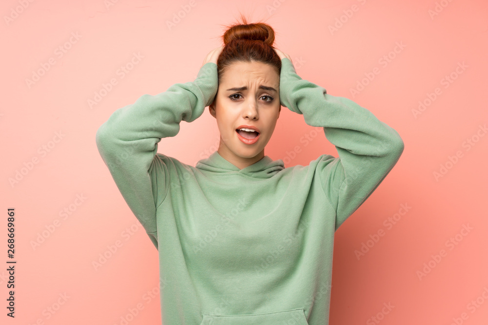 Young redhead woman with sweatshirt frustrated and takes hands on head Young redhead woman with sweatshirt frustrated and takes hands on head