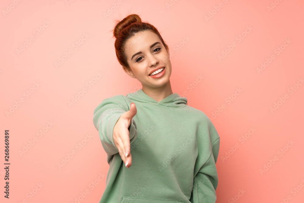 Young redhead woman with sweatshirt shaking hands for closing a good deal Young redhead woman with sweatshirt shaking hands for closing a good deal