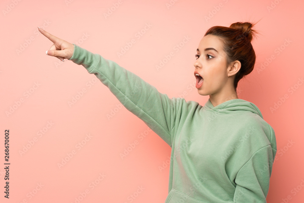 Young redhead woman with sweatshirt pointing away Young redhead woman with sweatshirt pointing away