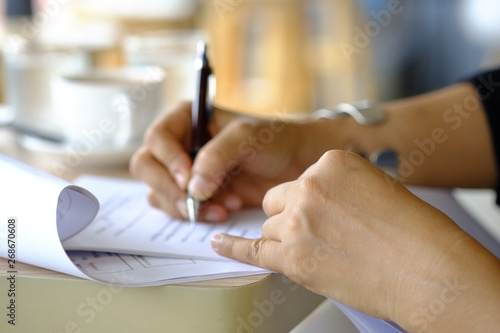 The hands of women who are writing books on various documents on the desk,reviewing the correctness before proposing in the next step.