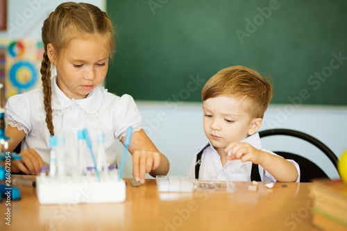 Knowledge is always yours. Cute Little girl helping her younger brother at classroom in school or pre-school photo
