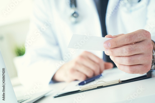 Wallpaper Mural Male physician hand holding and giving white blank calling card closeup in office. Contact information exchange, introducing gesture at formal meeting, personal or family doctor concept Torontodigital.ca
