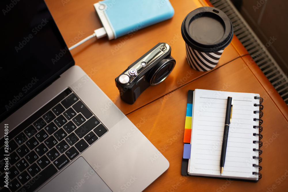 Work wooden desk of photographer with camera near cup of coffee, laptop, external hdd drive and empty notebook Work wooden desk of photographer with camera near cup of coffee, laptop, external hdd drive and empty notebook