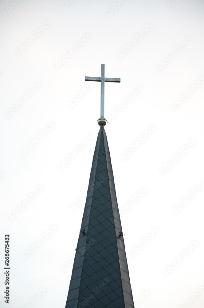 Spire with a cross on a catholic church building. Against the sky Spire with a cross on a catholic church building. Against the sky