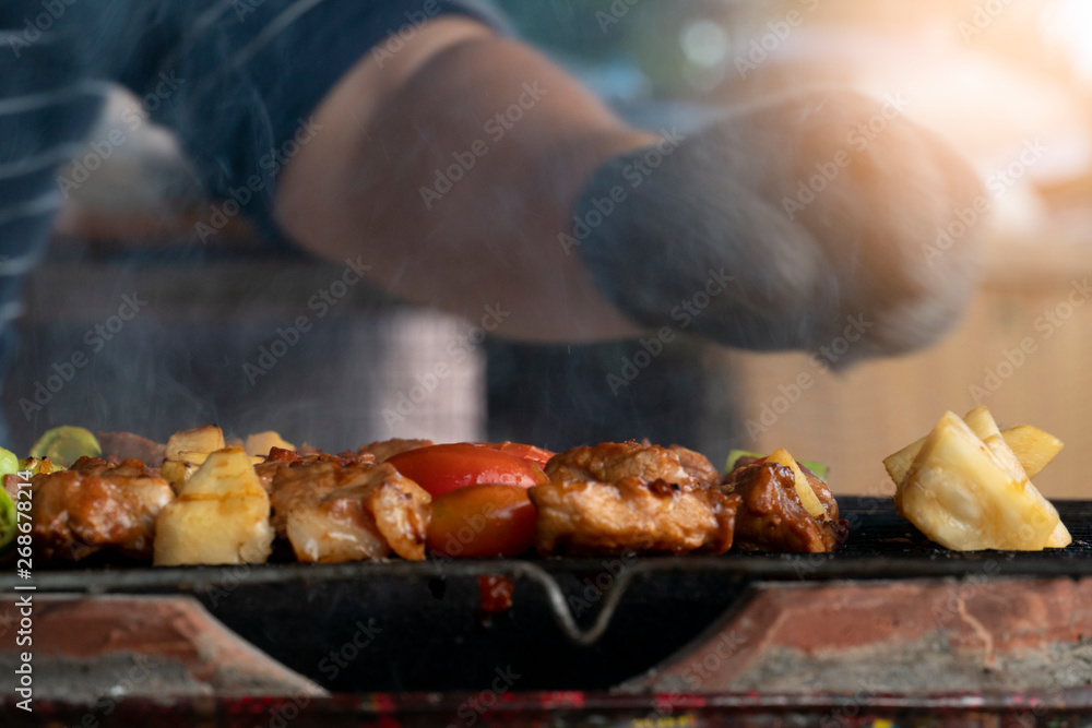 BBQ grilled on a steel grill and smoked in Thai style. Blurred of people take arms.