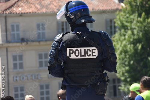 Helmeted police officer photographed from behind during a protest
