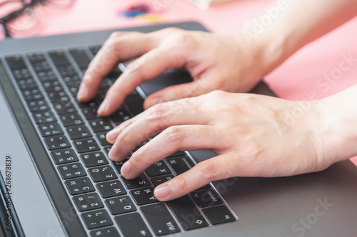 women typing on laptop in pink pastel colourful office with accessories