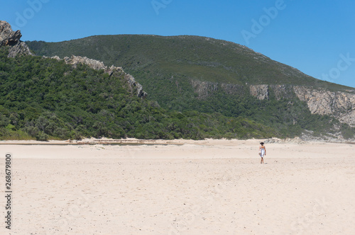 Woman in a summer hat and dress walking on the sand