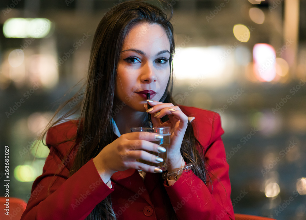 Young woman holding a drink at a night club outdoor Young woman holding a drink at a night club outdoor