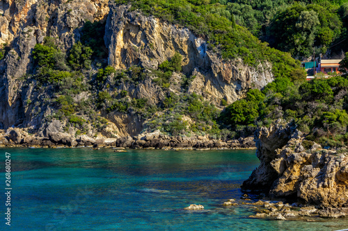 Beautiful landscape with sea, mountains and cliffs, green trees and bushes, rocks in a blue water. Corfu Island, Greece. 