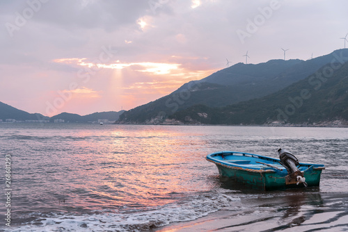 Blue yacht floating on the beach at sunset