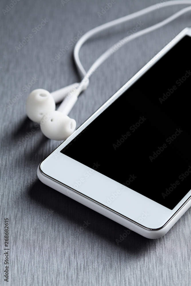 Modern mobile phone and headphones on a gray background Modern mobile phone and headphones on a gray background