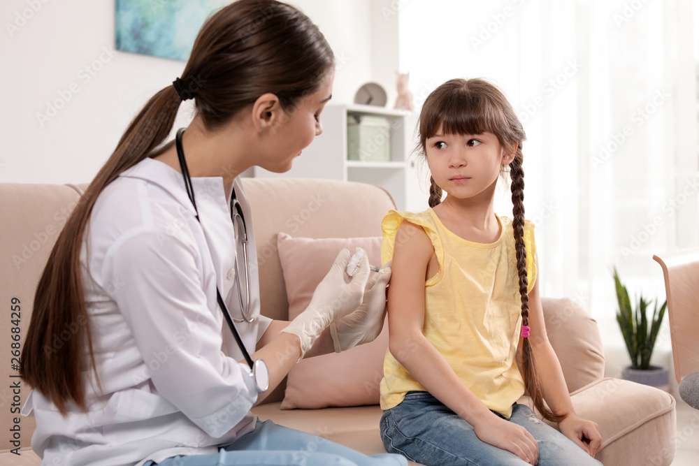 Family doctor vaccinating little child at home Family doctor vaccinating little child at home
